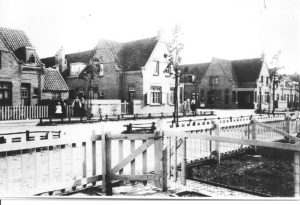 De fotograaf plaatste zijn statief in een van de voortuintjes van de huizen aan de De Lessepsstraat. Dat was voor de overburen al aanleiding genoeg om ‘haastje repje’ het goeie goed aan te trekken en de verrichtingen vanaf de overzijde nauwlettend te volgen. De foto werd genomen richting Amsterdamsestraatweg, zo rond 1920.