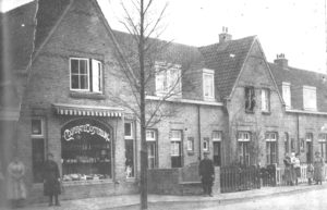 De tabakswinkel van ‘Coöperatie Oostenburg’ op de hoek van de De Lessepsstraat en de Galvanistraat. Toen de fotograaf langskwam om dit plaatje van de straat te maken, kwamen daar de bewoners even voor naar buiten.