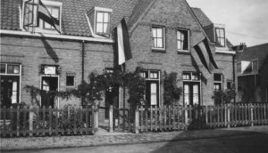 Prachtig versierde woning in de Marconistraat, ter gelegenheid van de thuiskomst van de Nederlands-Indië-ganger D. Mol. Van bijna iedere woning wappert een vlag. Boven de deur van nummer 20 (Hij staat open) hangt de tekst: Welkom Thu